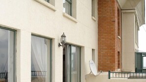 A building with large windows, a satellite dish, and a tiled patio area.