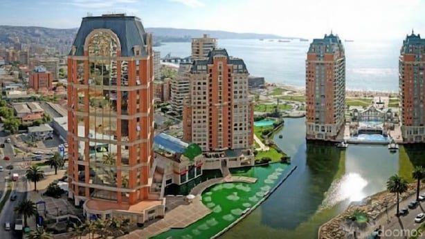 A high-rise hotel with multiple floors, a central courtyard, and a view of a body of water.