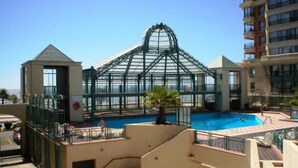 A hotel with a large glass greenhouse structure, a swimming pool, and a staircase leading to an upper level.