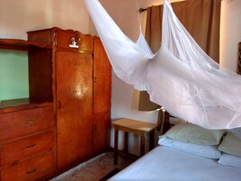 Un dormitorio con un armario de madera, una mesita de noche y una cama con ropa de cama blanca.