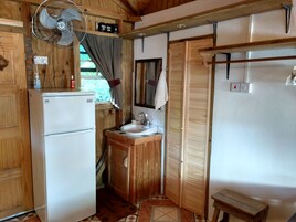 Una cocina compacta con refrigerador, lavamanos y armarios de madera.