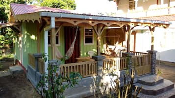 Una casa verde con un porche, una hamaca y una pequeña zona de estar al aire libre.