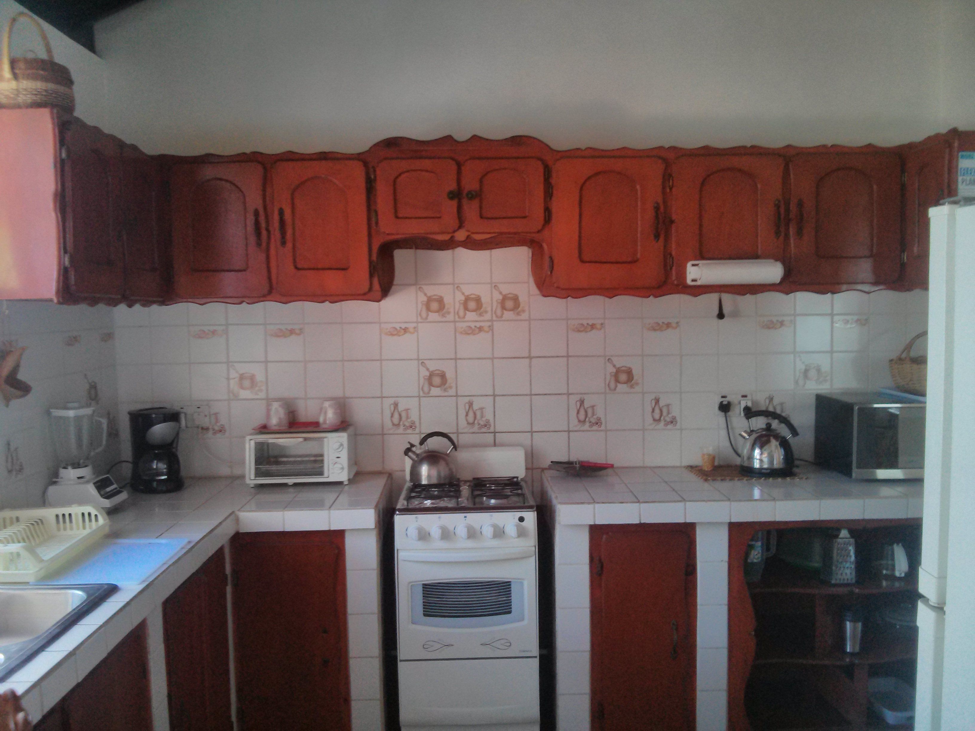 A kitchen with wooden cabinets, a stove, a microwave, and a toaster.
