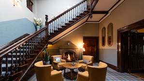 A grand staircase leading to a fireplace with four armchairs and a coffee table in the center.