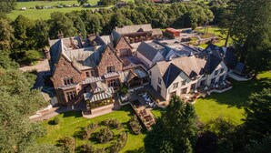 A large estate with multiple buildings, expansive gardens, and a scenic countryside backdrop.