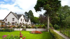 A large house with a well-maintained garden, a paved pathway, and a fenced area.