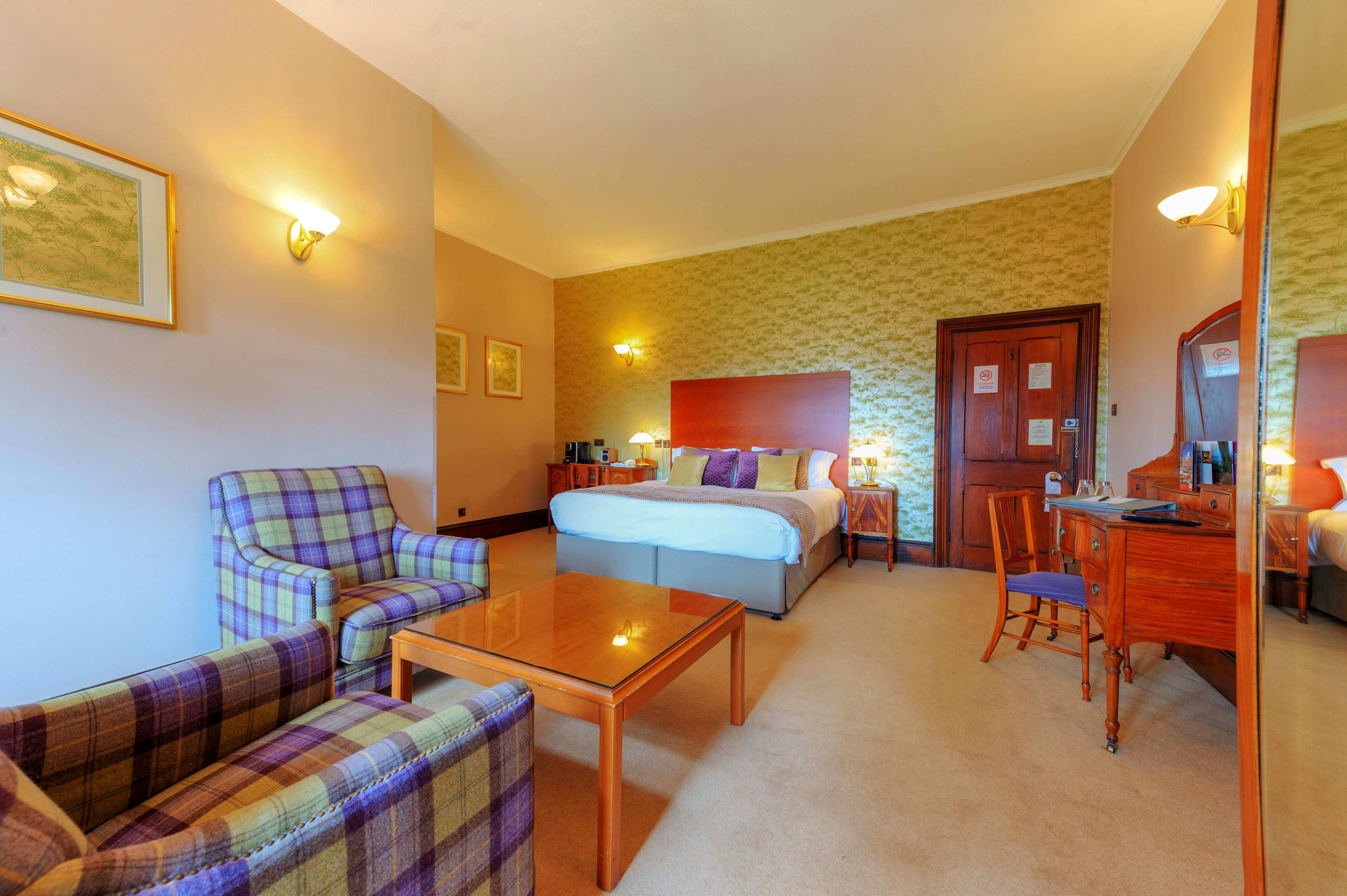 A hotel room with a bed, a sofa, a desk, and a chair.