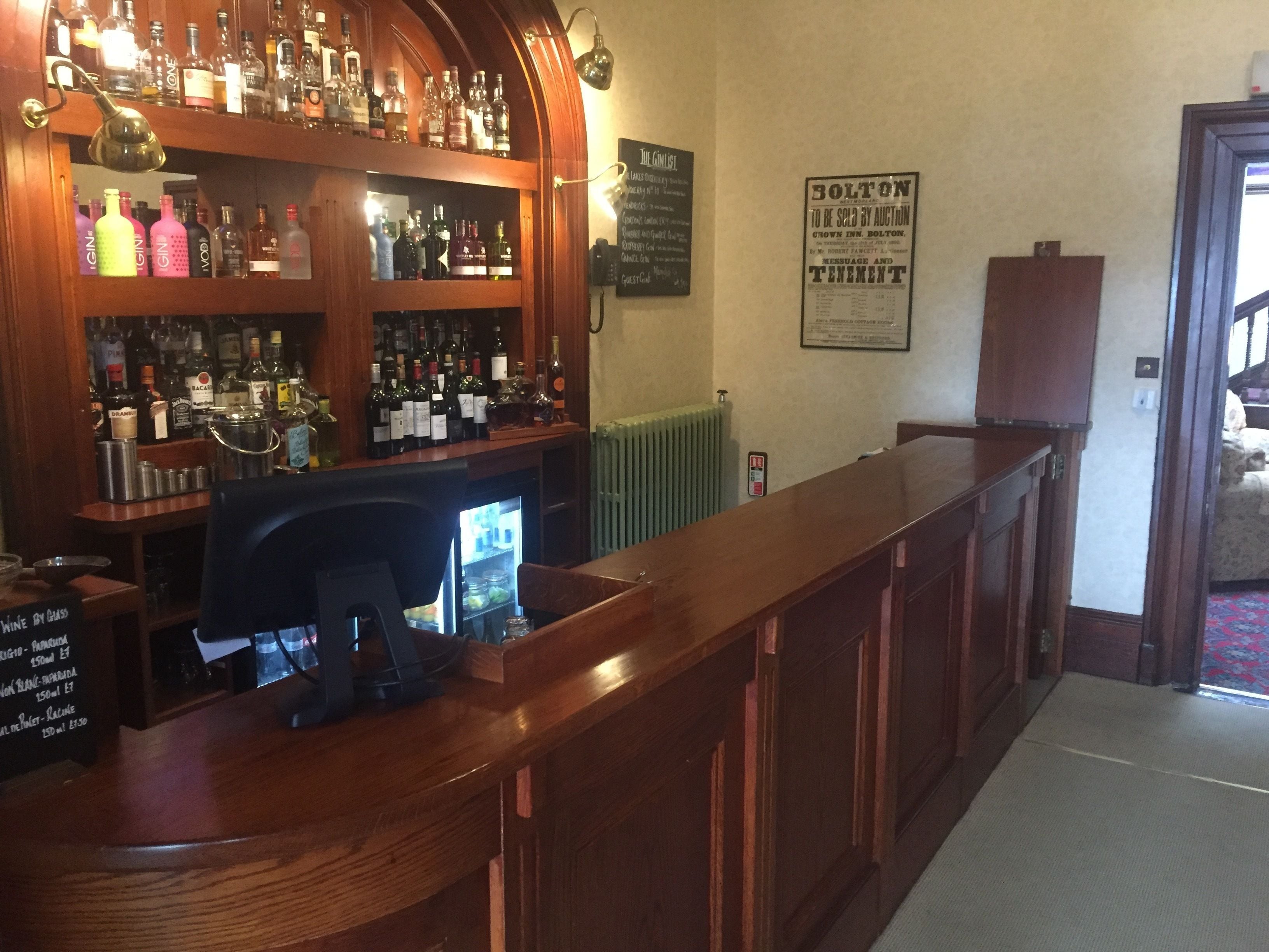 A bar area with shelves of liquor bottles, a cash register, and a sign indicating the bar is open for sale by auction.