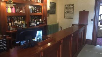 A bar area with shelves of liquor bottles, a cash register, and a sign indicating the bar is open for sale by auction.