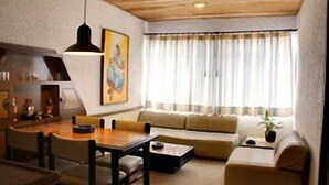 A modern living room with a dining area, featuring a sofa set, a coffee table, and a dining table with chairs. - Suites Real 85 (Bogota)