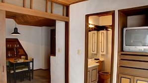 A room with a wooden ceiling, a small table with chairs, a white sink, and a television on a wooden cabinet. - Suites Real 85 (Bogota)