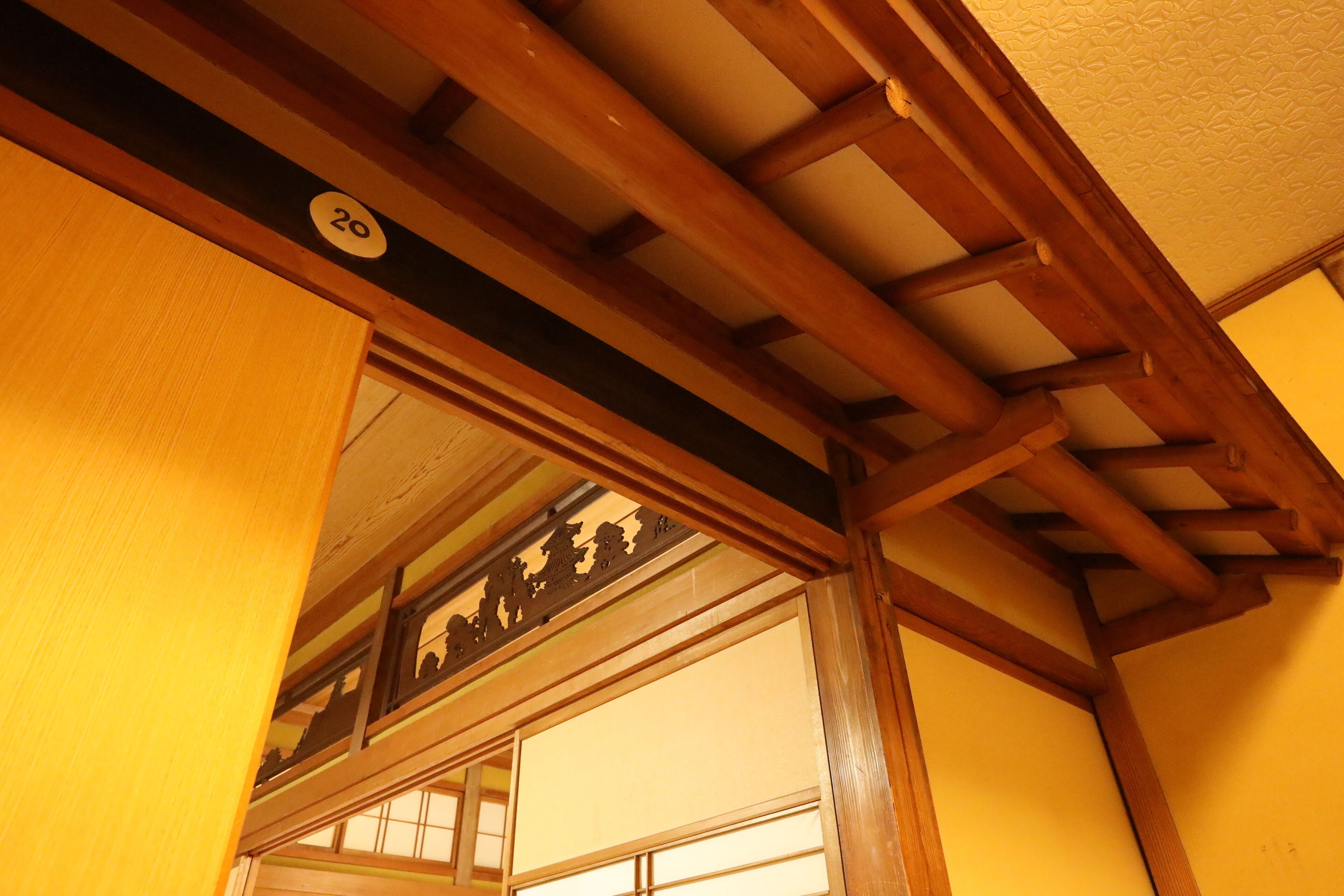 Een traditioneel Japans interieur met houten balken en een schuifdeur.