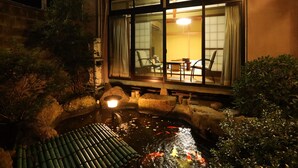 A traditional Japanese garden with a koi pond, stone lanterns, and a wooden bridge. - Daibutsu Ryokan (Takaoka)