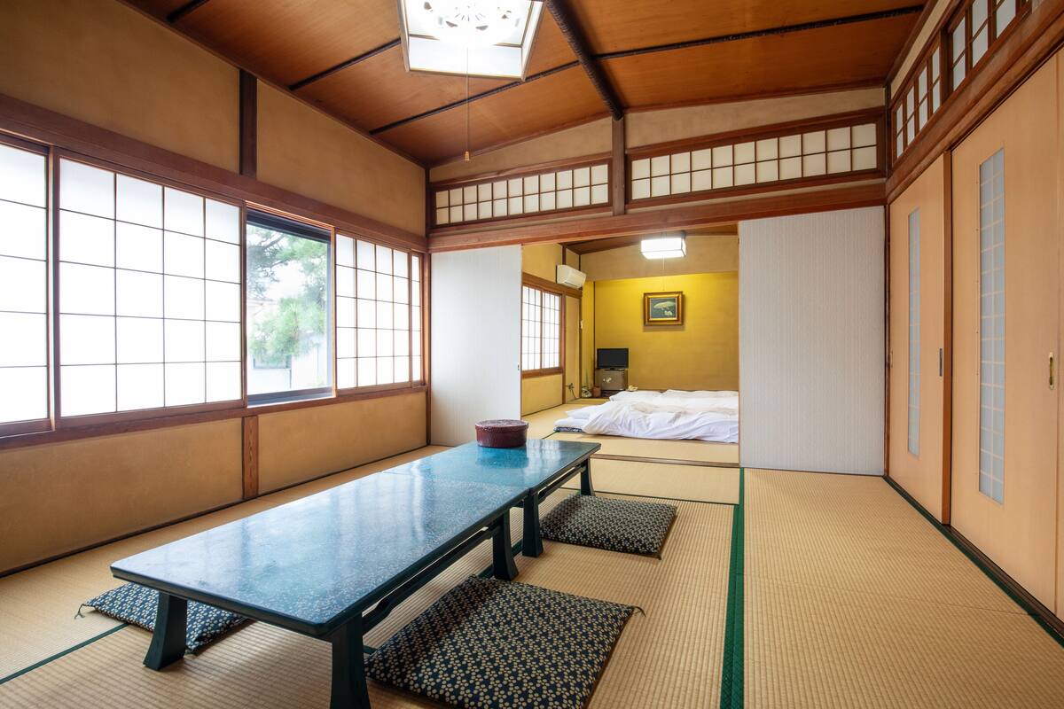 Ein traditioneller japanischer Raum mit Tatami-Boden, einem niedrigen Tisch und Schiebetüren.