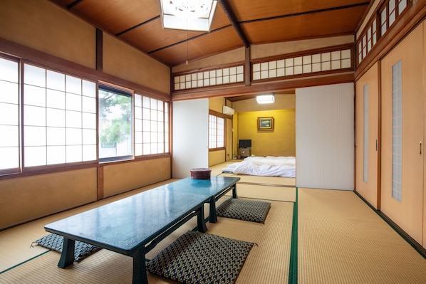 Una habitación japonesa tradicional con suelo de tatami, una mesa baja y puertas correderas.