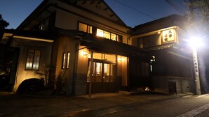 A traditional building with a well-lit entrance and a signboard. - Daibutsu Ryokan (Takaoka)