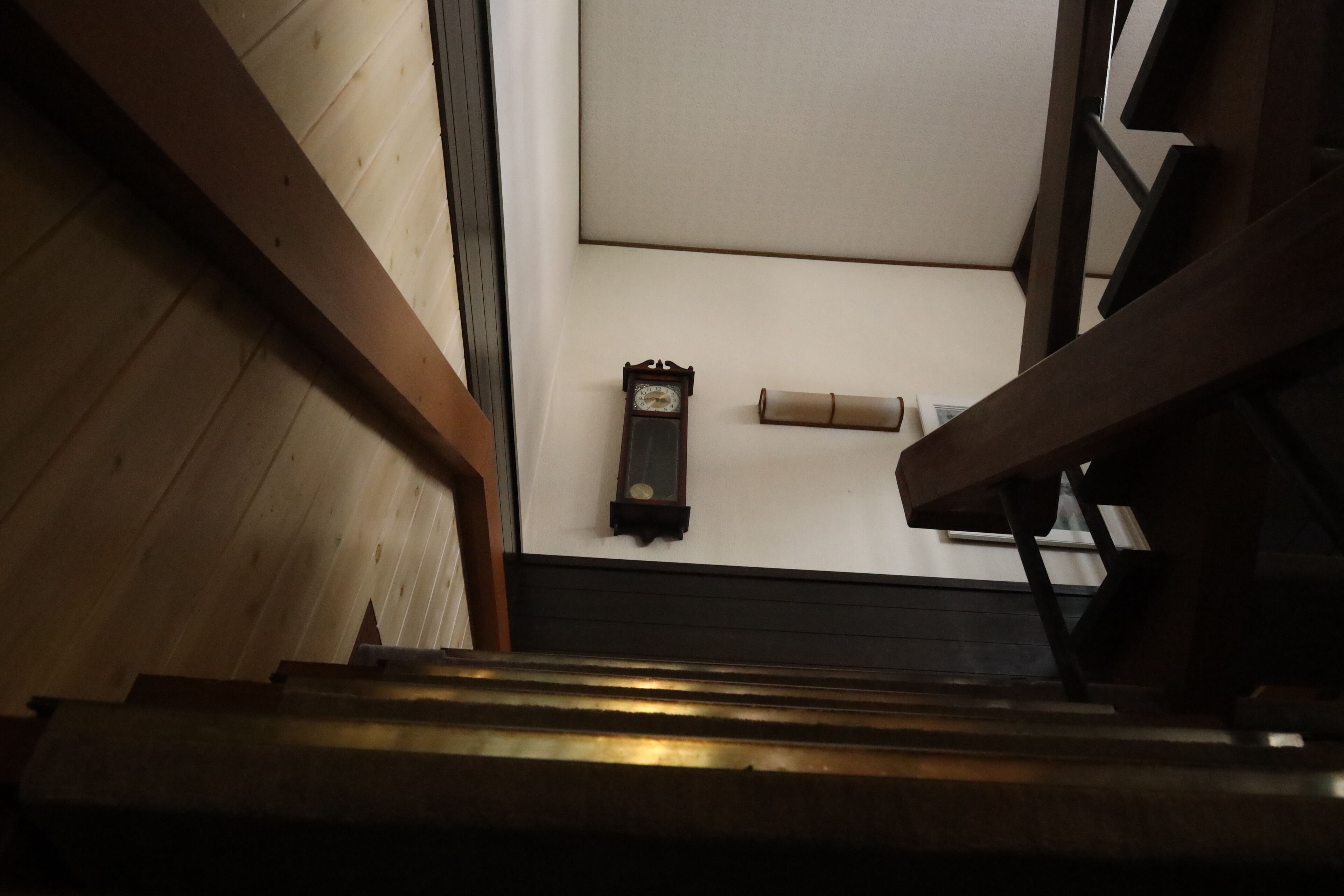 Un escalier en bois avec une horloge au mur.