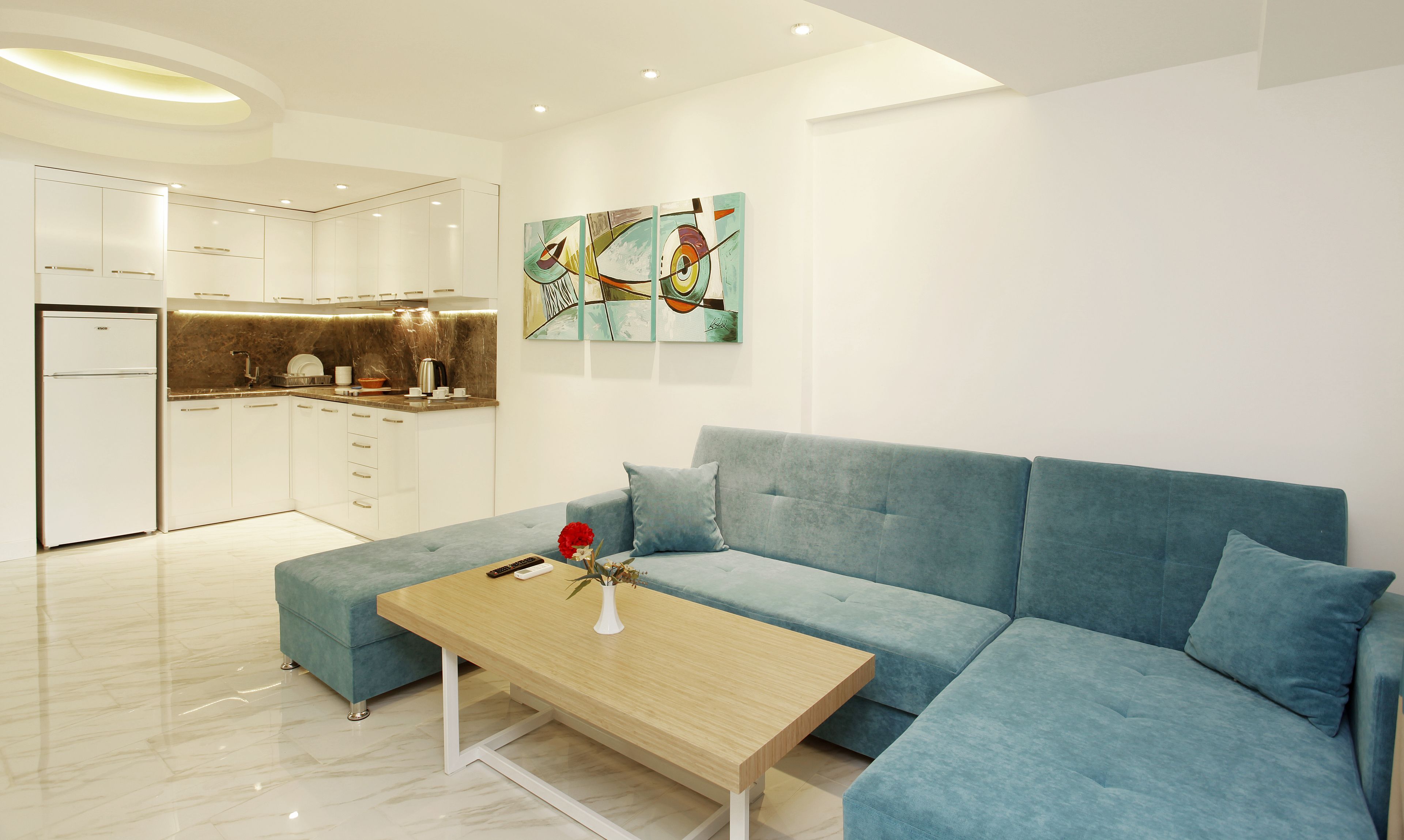 Een moderne woonkamer met een blauwe bank, een houten salontafel en een keuken op de achtergrond.