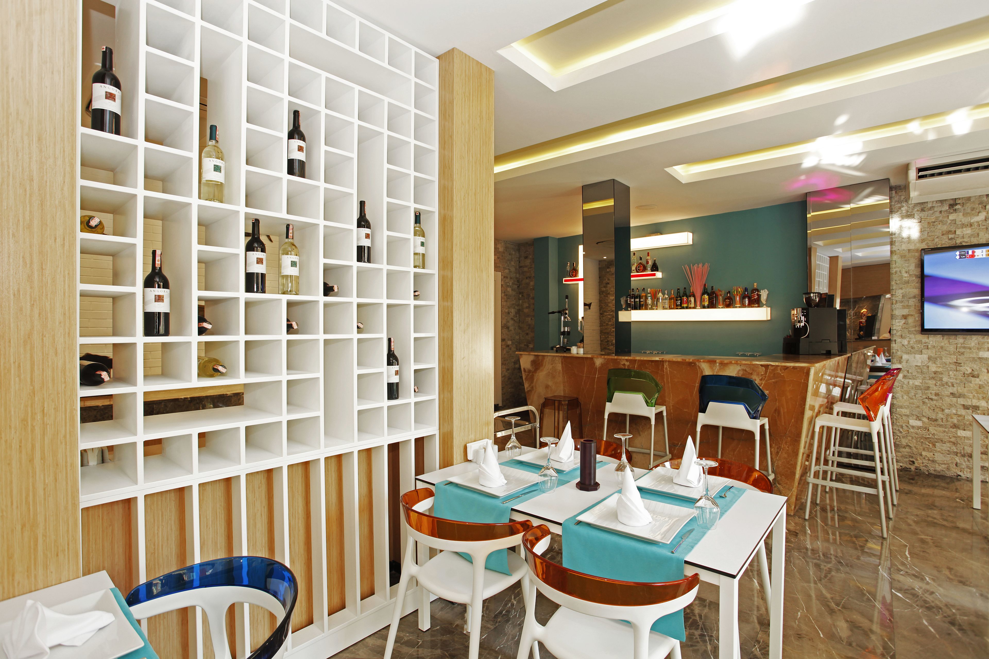 Un restaurant moderne au décor blanc et en bois, avec un espace bar et un écran de télévision.