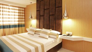 A hotel room with a large bed, a bedside table, a phone, and a wall-mounted light fixture. - Kleopatra Suit Hotel  (Alanya)