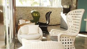 A modern lounge area with wicker furniture, a glass partition, and a stone wall. - Kleopatra Suit Hotel  (Alanya)