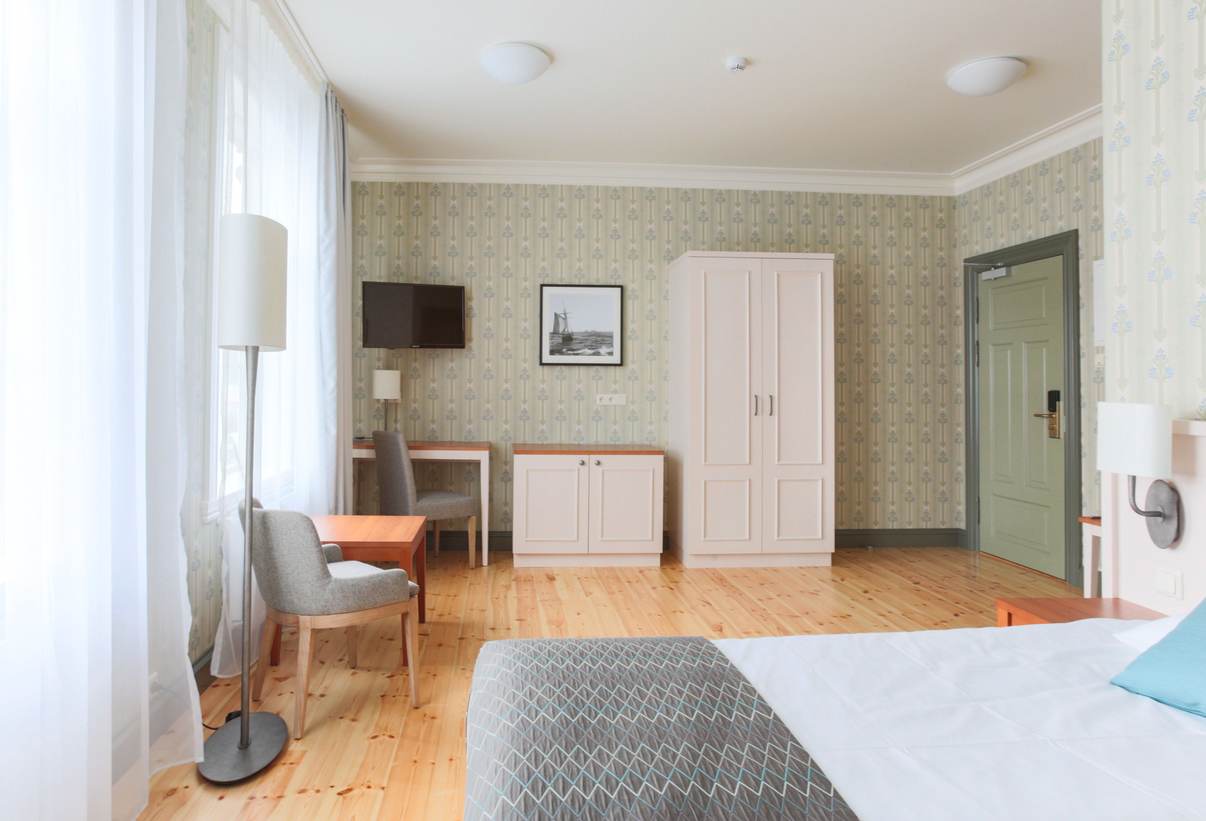 Une chambre d’hôtel comprenant un lit, un bureau, une chaise, une armoire et un téléviseur.