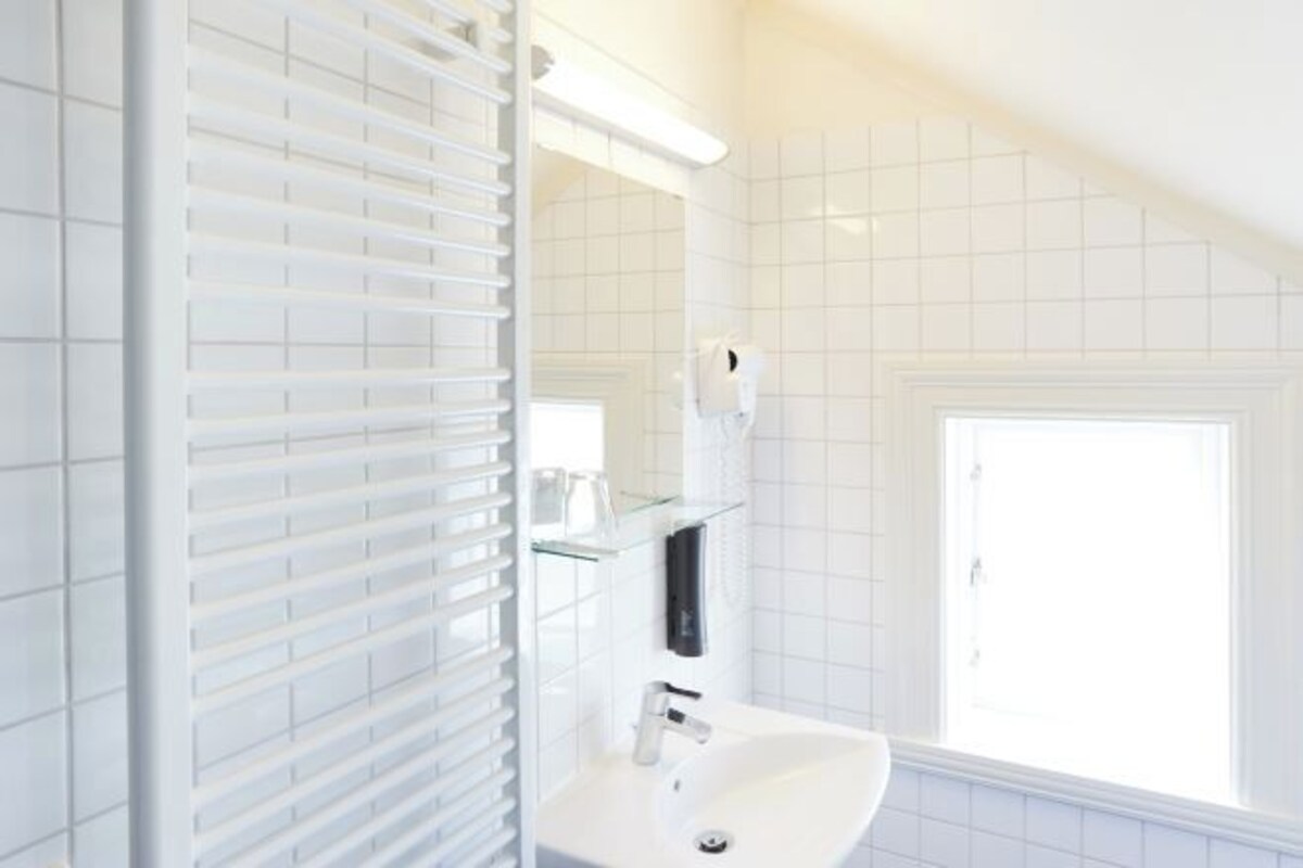 A bathroom with a white sink, a mirror, and a window.