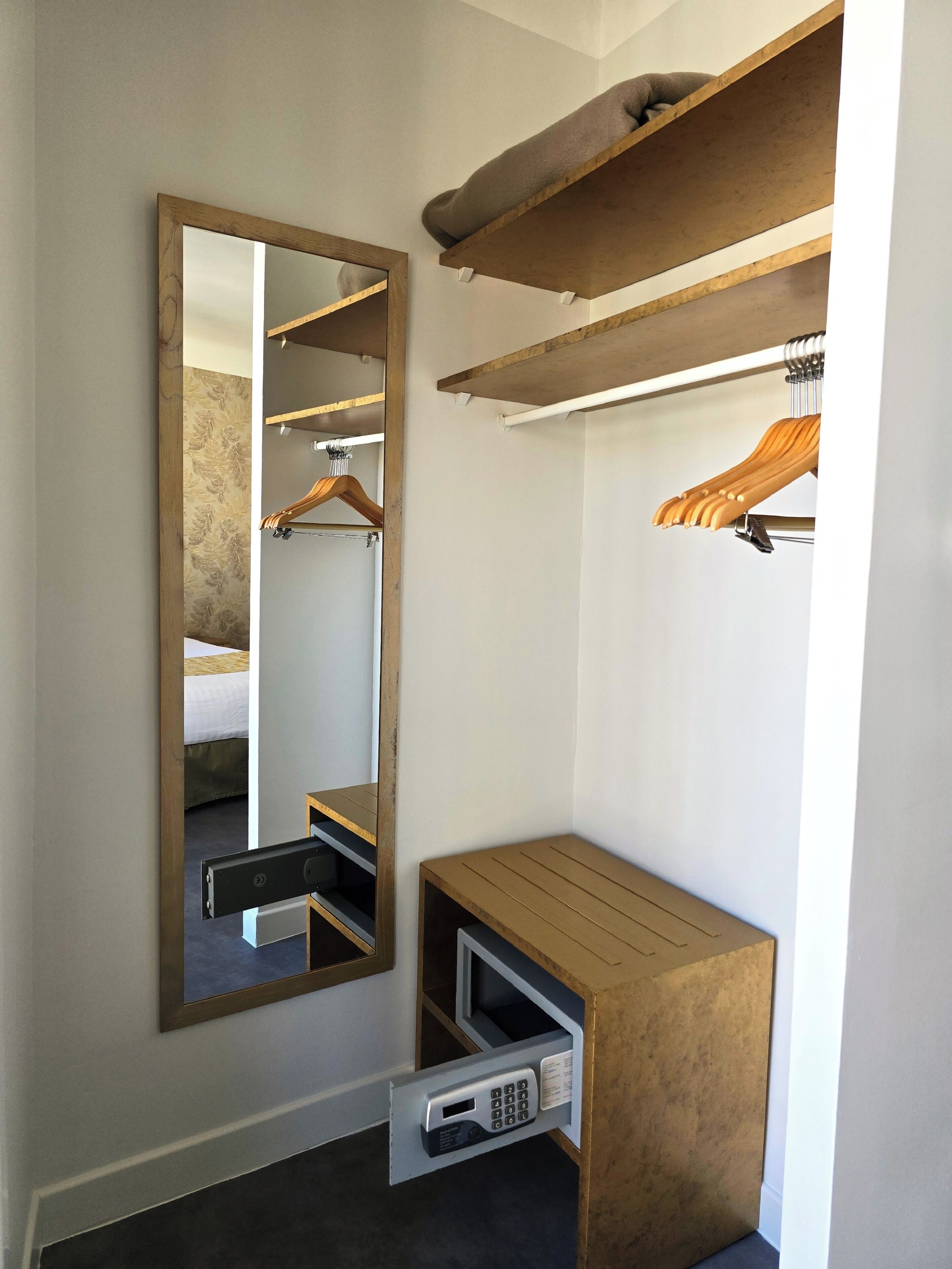 A modern bedroom with a wooden wardrobe, a mirror, and a built-in bench.