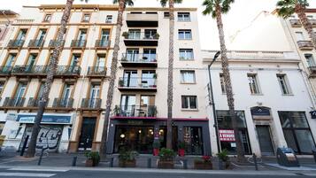 A multi-story hotel with balconies, a ground-floor restaurant, and a visible storefront.