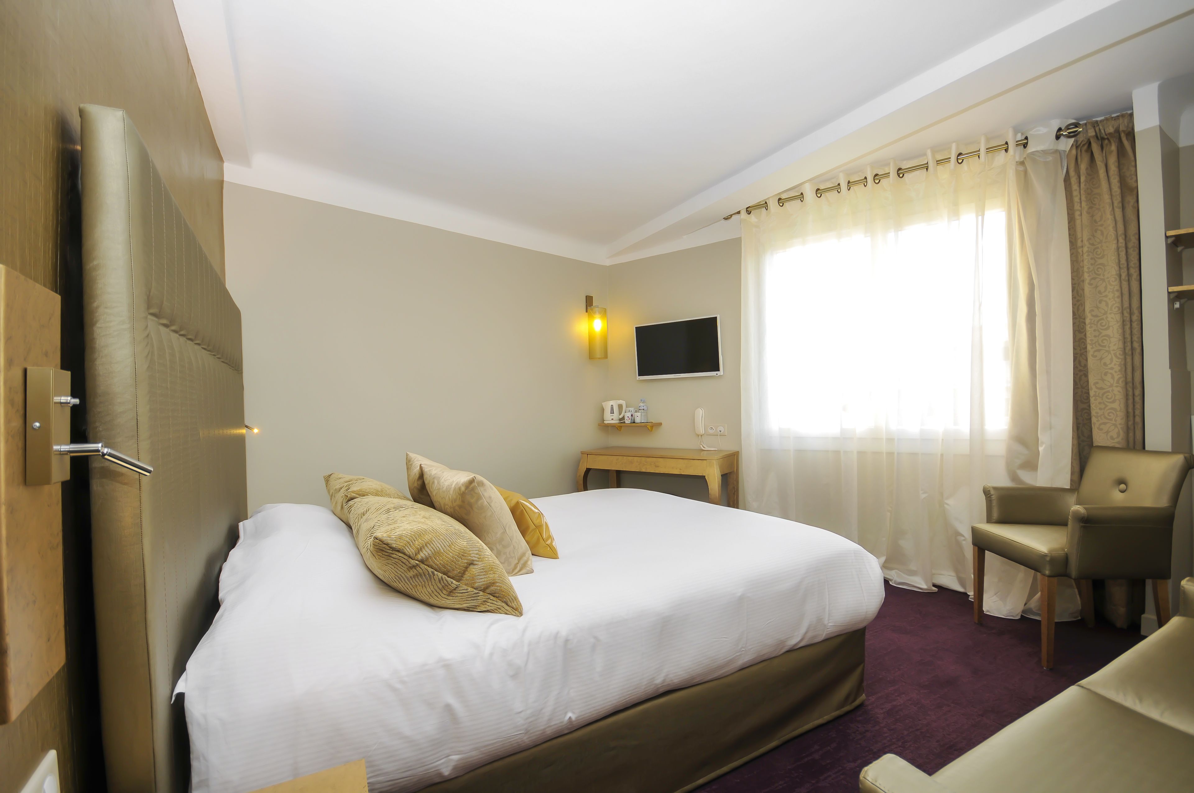 A hotel room with a large bed, a television, a small table, and a chair.