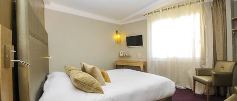 A hotel room with a large bed, a television, a small table, and a chair.