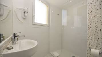A bathroom with a white sink, a hairdryer, and a shower with a patterned wall.
