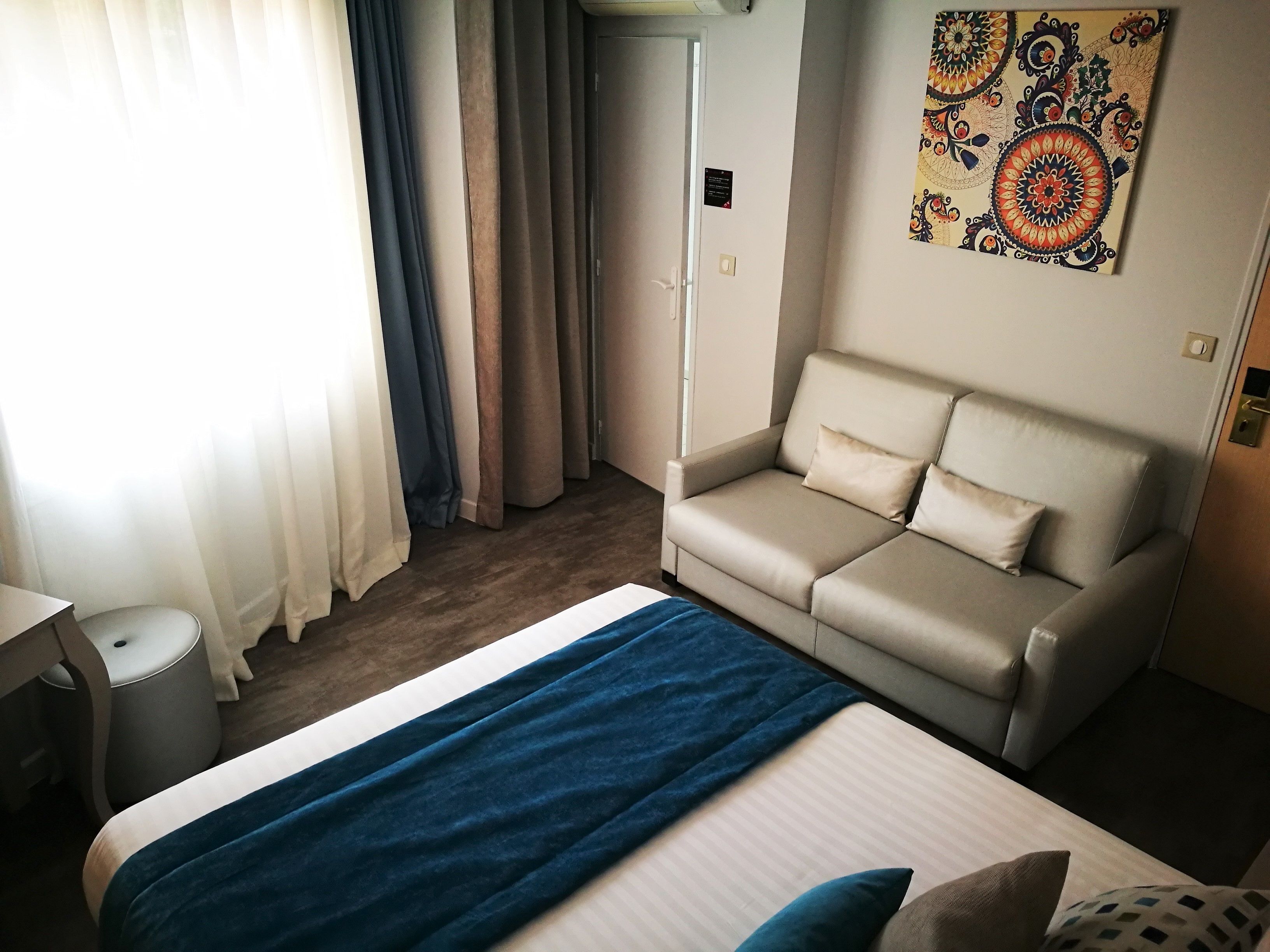 A hotel room with a bed, a sofa, a desk, and a wardrobe.
