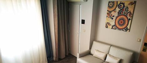 A hotel room with a bed, a sofa, a desk, and a wardrobe.