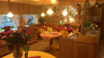 Enjoy a warm and inviting dining experience with round tables, a sofa, and a vase with fresh flowers.