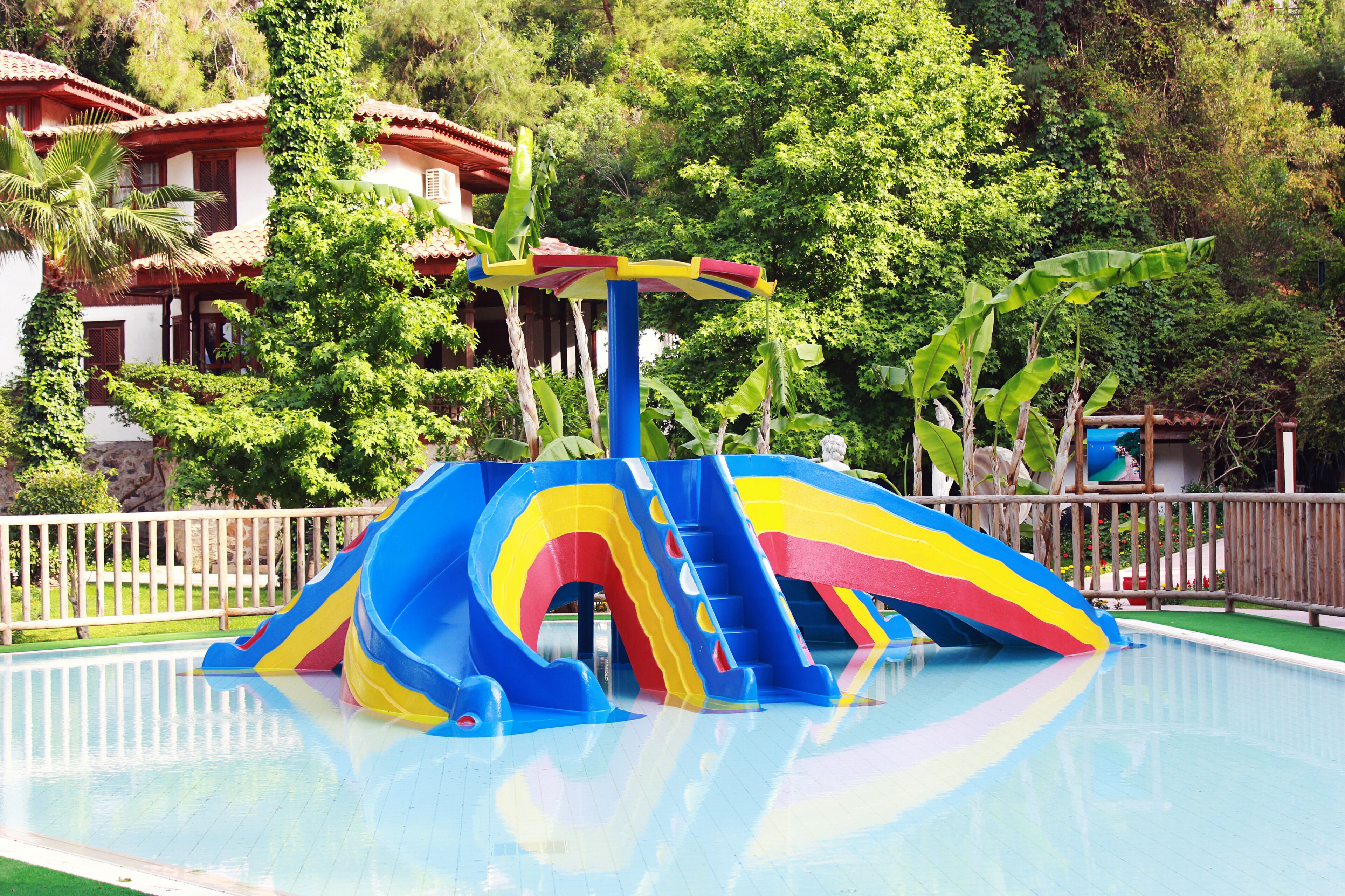 A pool with a colorful slide and stairs.