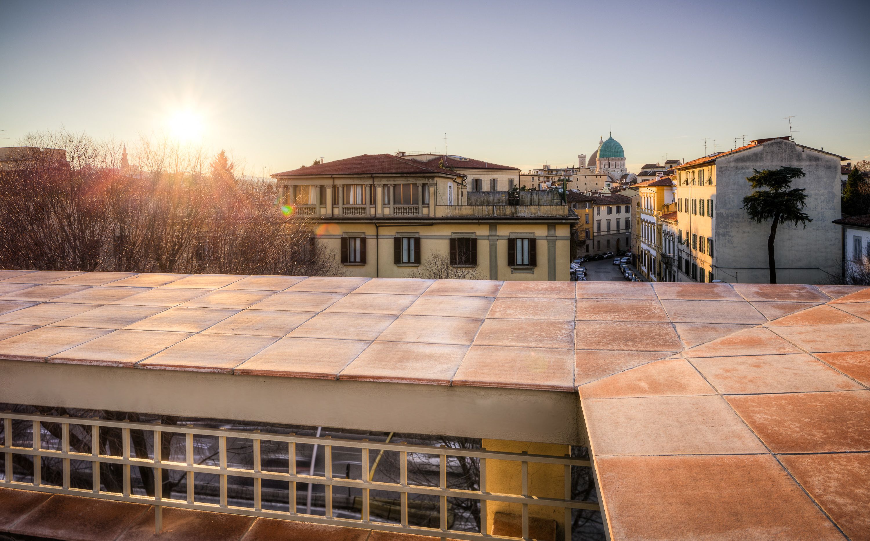 A view of a cityscape with buildings, a clear sky, and the sun setting or rising.