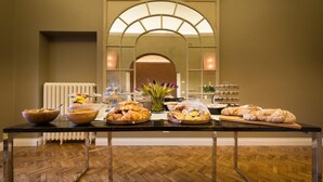 A buffet table with various food items and a vase of flowers. - Forte16 View & Spa (Florence)