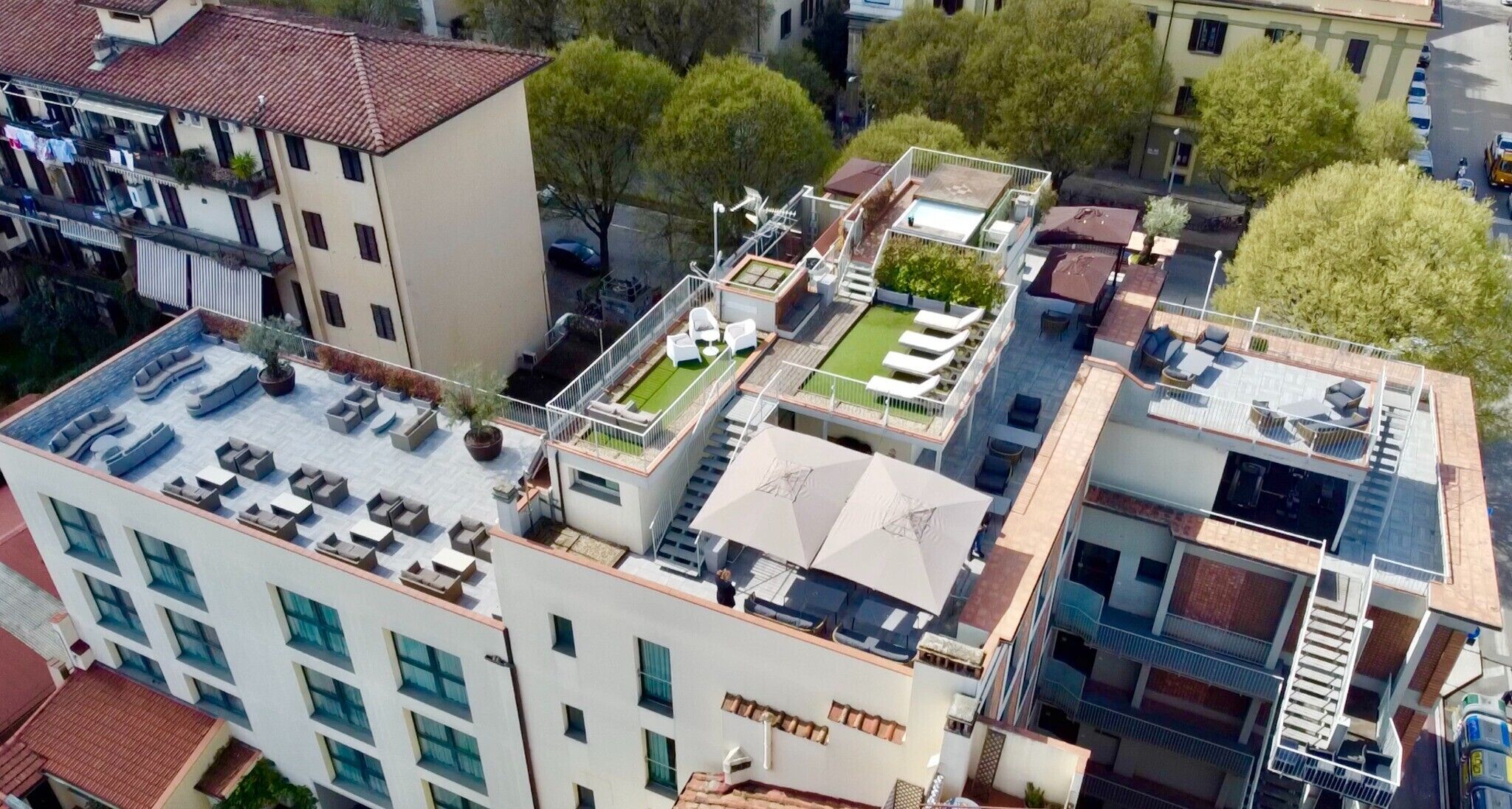 A multi-story building with rooftop terraces, outdoor seating, and a pool area.
