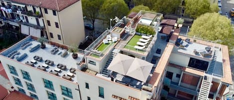 A multi-story building with rooftop terraces, outdoor seating, and a pool area.