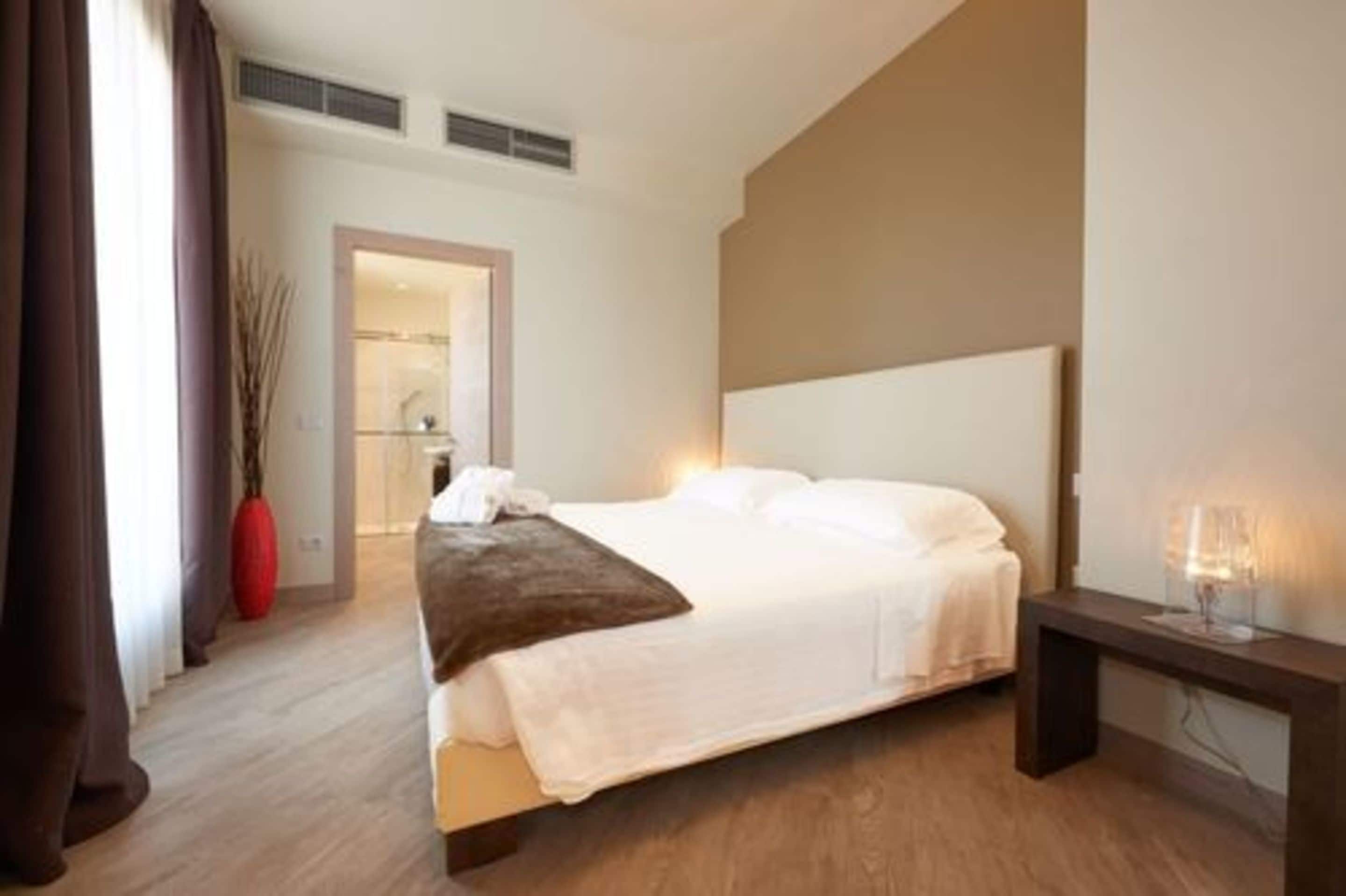 A modern hotel room with a large bed, a bedside table, and a nightstand.