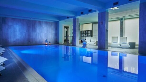 An indoor swimming pool with clear water, a tiled floor, and a few lounge chairs along the side. - Forte16 View & Spa (Florence)