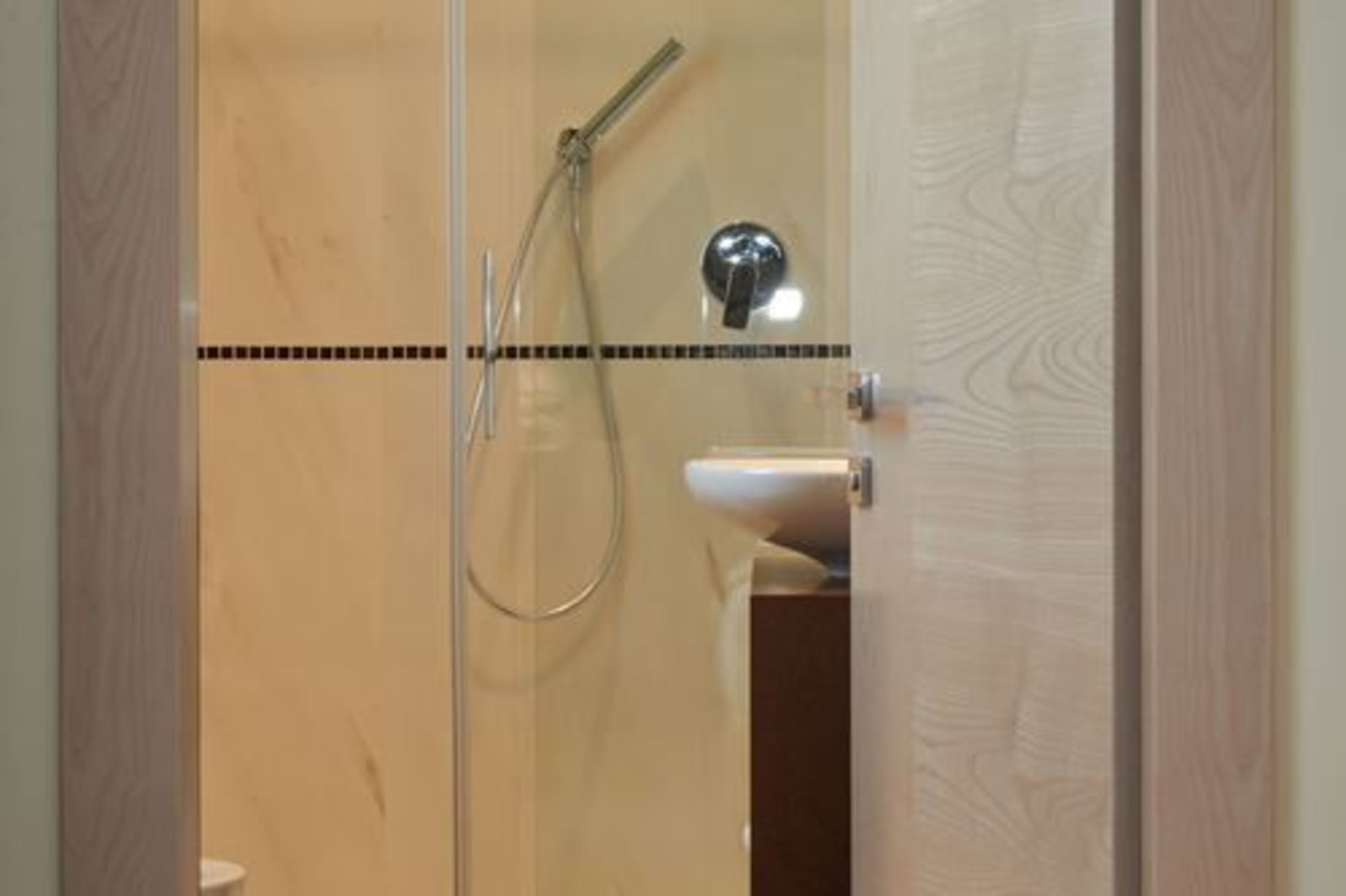 A glass-enclosed shower area with a handheld showerhead and a wall-mounted faucet.