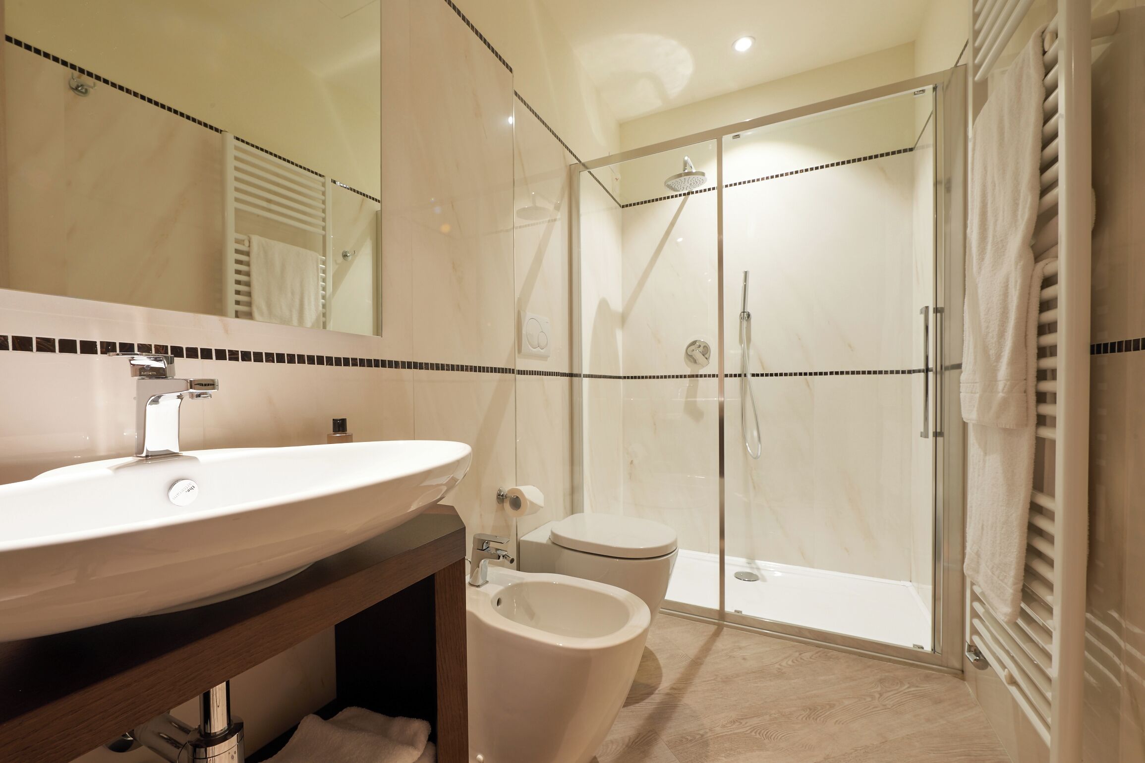 A modern bathroom with a large sink, toilet, and glass-enclosed shower.