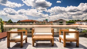 A rooftop terrace with three wooden chairs and a bench, offering a view of a cityscape with historic buildings and a dome structure. - Forte16 View & Spa (Florence)