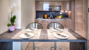 A modern dining area with a marble countertop, two chairs, and a table set for two with plates, cutlery, and glasses. - Forte16 View & Spa (Florence)