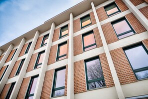 A multi-story building with a grid of windows and brick accents.