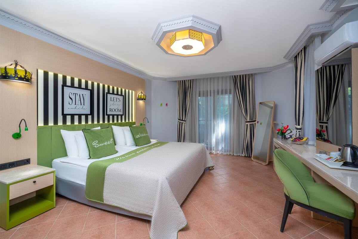 Une chambre d’hôtel avec un lit bien fait, un bureau avec une chaise, un miroir et une armoire.