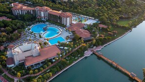 An aerial view of a resort with multiple swimming pools, a marina, and lush greenery. - Selectum Family Resort Belek (Serik)
