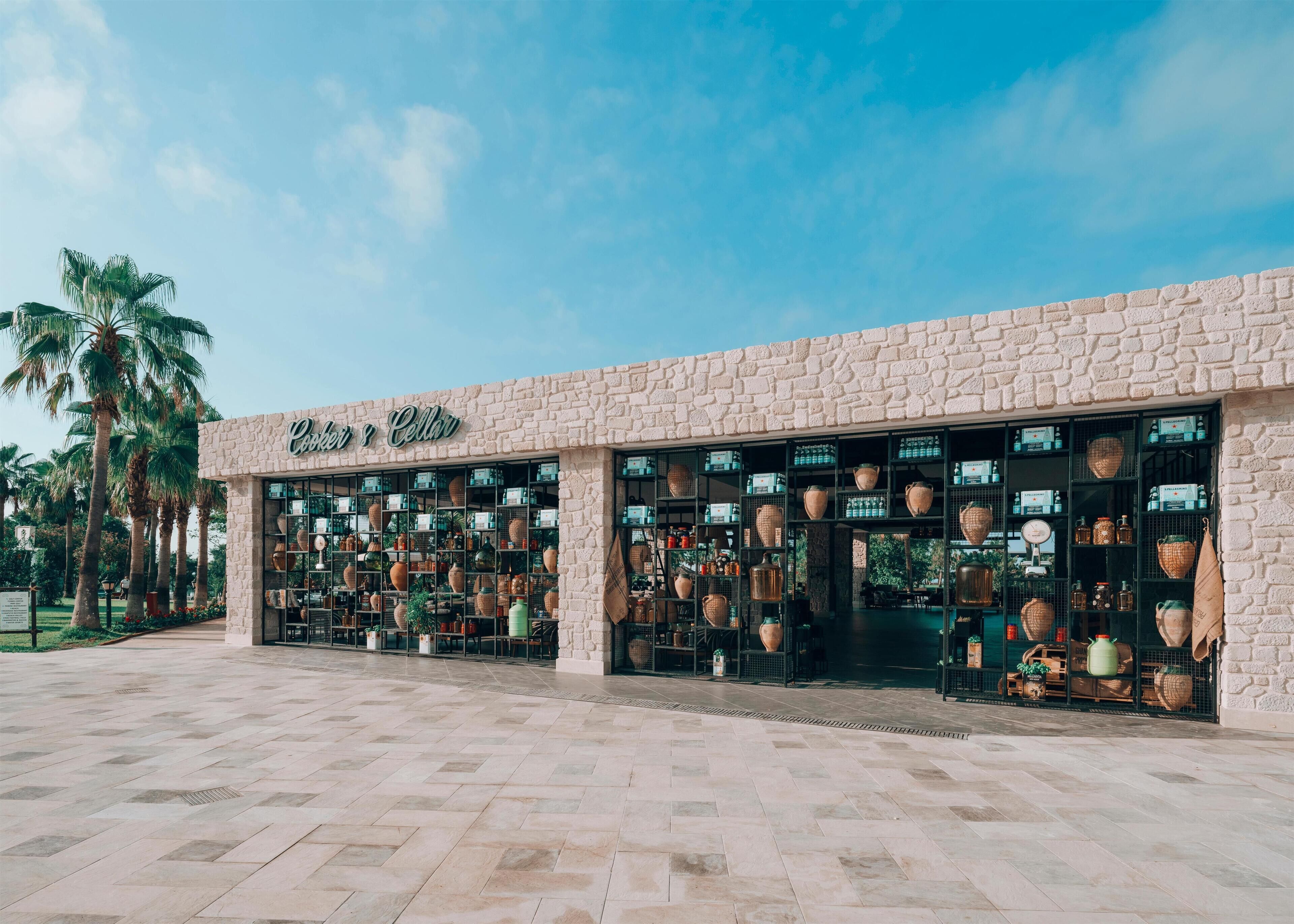 A storefront with a stone facade and large display windows filled with pottery and ceramics.